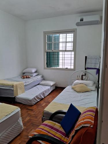 Cette chambre comprend 3 lits et une fenêtre. dans l'établissement Casa Térrea SP Expo e C Paralimpico, à São Paulo