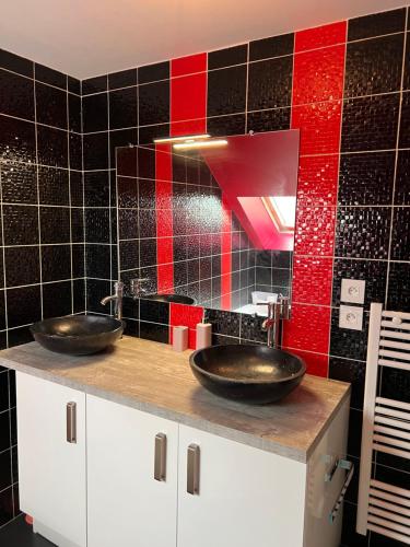 - deux lavabos dans une salle de bains revêtue de carrelage rouge et noir dans l'établissement GITES au calme, à Soudan