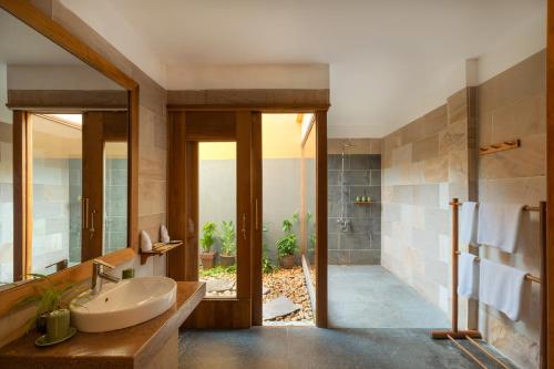 a bathroom with a sink and a mirror and a shower at Green Bay Phu Quoc Resort & Spa in Phu Quoc