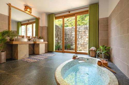 ein Bad mit einer großen Badewanne in der Mitte in der Unterkunft Green Bay Phu Quoc Resort & Spa in Phu Quoc
