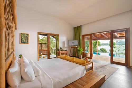Schlafzimmer mit einem großen weißen Bett und Glasschiebetüren in der Unterkunft Green Bay Phu Quoc Resort & Spa in Phu Quoc