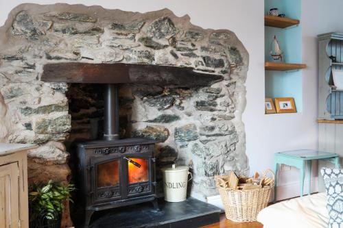 a stone fireplace in a living room with a stove at Beautiful Victorian home with private pet-friendly garden sleeps 6 in Holyhead