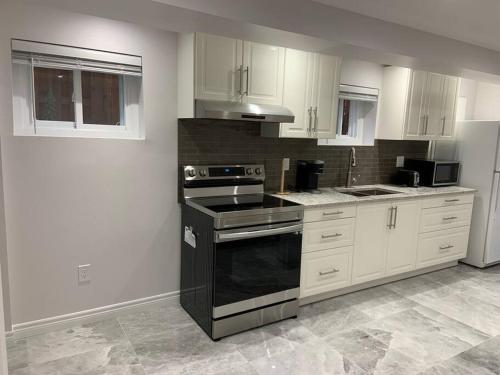 a kitchen with white cabinets and a black stove top oven at Luxurious brand new ground level apartment in Mississauga