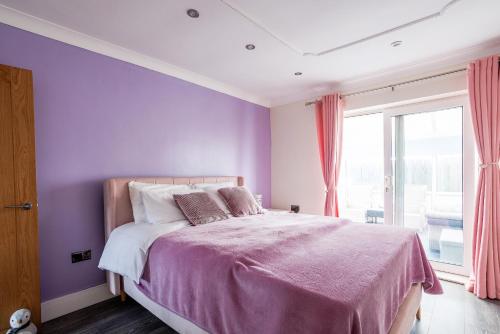a bedroom with purple walls and a bed with pillows at SUMMER BREEZE in Horden