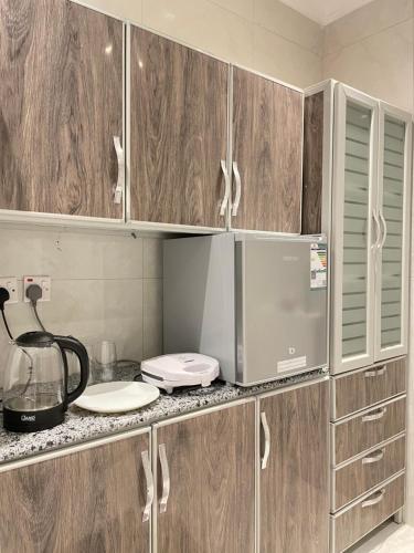 a kitchen with wooden cabinets and a microwave at شقه استديو حي بالمروج in Riyadh