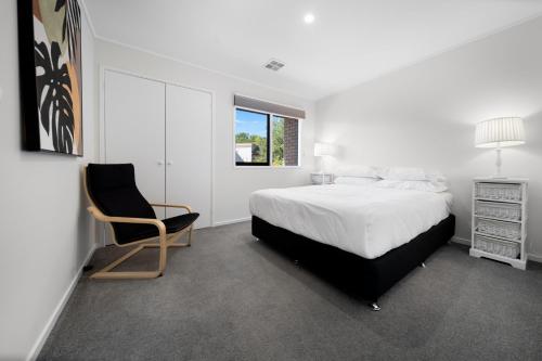 una camera bianca con un letto e una sedia di Gorgeous 2-Bed Townhouse with Patio, BBQ & Parking a Kingston 