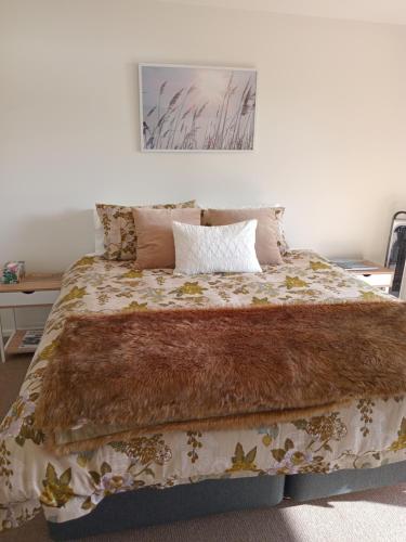 a bed with a brown blanket and pillows on it at The Views in Dunedin