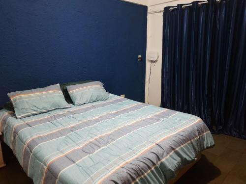 um quarto com uma cama com uma parede azul em Departamento completo en edificio Camilo Recalde 477 em Ciudad del Este