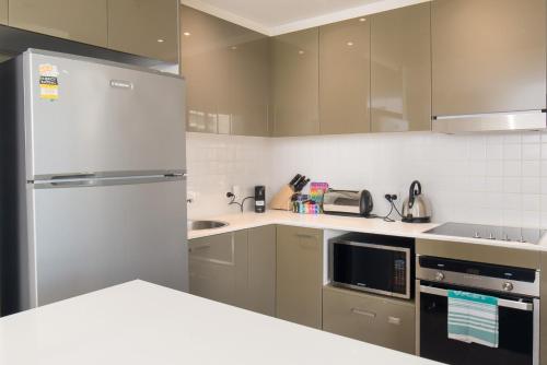 una cocina con nevera y electrodomésticos de acero inoxidable en Central 1-Bed with Parking BBQ and Indoor Pool, en Canberra