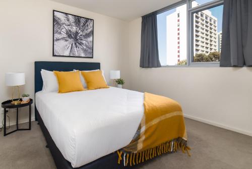 a bedroom with a large white bed with yellow pillows at Central 1-Bed with Parking BBQ and Indoor Pool in Canberra
