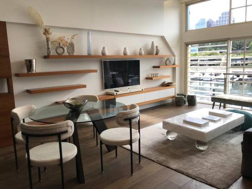 een woonkamer met een tafel en stoelen en een televisie bij Harbour View Woolloomooloo in Sydney