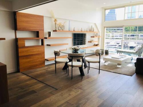 een woonkamer met een tafel en stoelen en een groot raam bij Harbour View Woolloomooloo in Sydney
