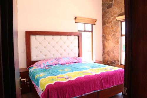 a bedroom with a large bed with a colorful bedspread at La Cuadra Cabaña 2 in Zacatlán