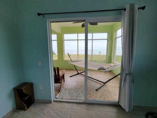a room with a sliding glass door with a hammock at Tranquil Waterfront Escape in Orange Walk