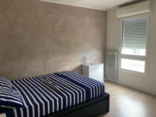 - une chambre avec un lit rayé bleu et blanc et une fenêtre dans l'établissement Appartement T2 Cozy avec Parking, à Argenteuil