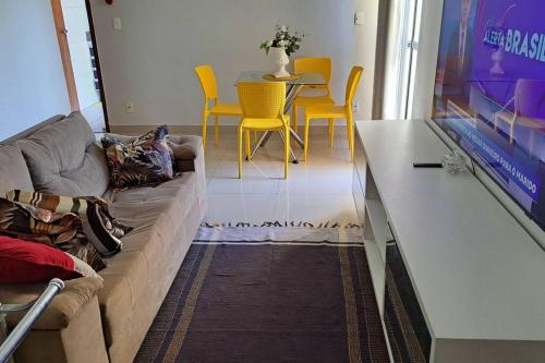 a living room with a couch and a table with yellow chairs at Apartamento na Ponta Negra, 2 quartos, sendo uma suite in Manaus