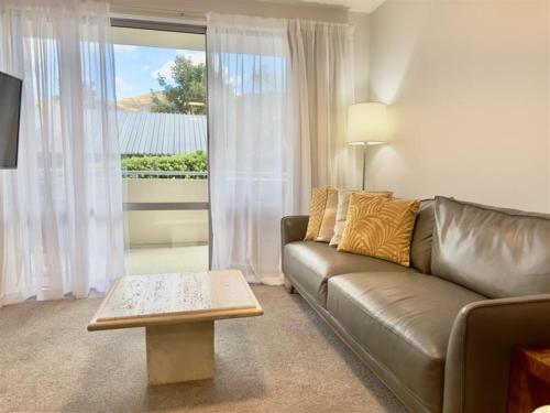 a living room with a leather couch and a table at Belvedere Apartments in Wanaka