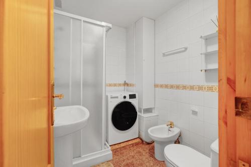 a bathroom with a toilet sink and a washing machine at A spacious and cozy apartment. in Torrevieja