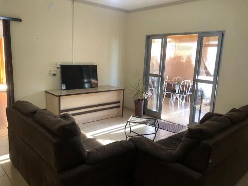 ein Wohnzimmer mit 2 Ledersofas und einem TV in der Unterkunft Pousada Abba Pai in Maracaju