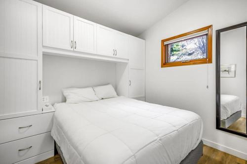 Cozy Cottage by the Lakeshore #4 في West Kelowna: غرفة نوم بيضاء بها سرير ونافذة
