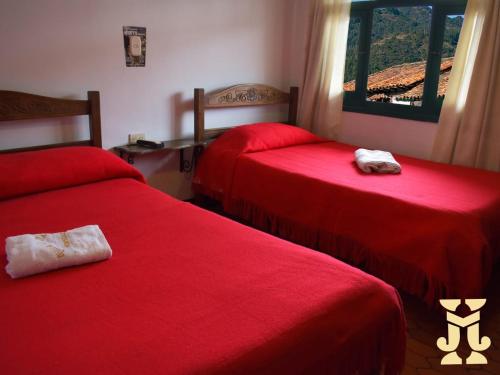 ein Hotelzimmer mit 2 Betten mit roter Bettwäsche in der Unterkunft Hotel Villa de Mongui in Monguí