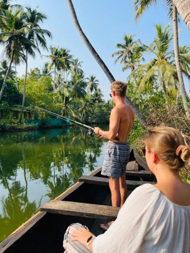 a man and a woman fishing on a boat at Riverrootsstays in Munroe Island
