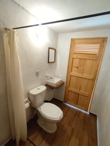 a bathroom with a toilet and a wooden door at Glamping De la Vereda in Cuetzalán del Progreso