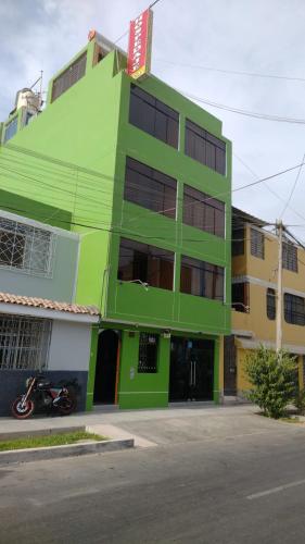 un bâtiment vert avec une moto garée devant lui dans l'établissement HOSPEDAJE ICA, à Ica