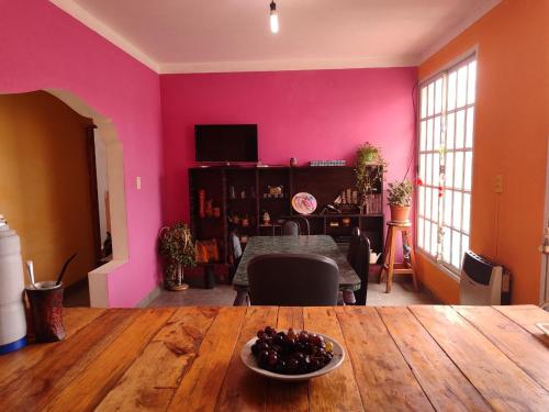 una sala de estar con paredes rosas y una mesa con un bol de fruta en VelayWasi en Humahuaca