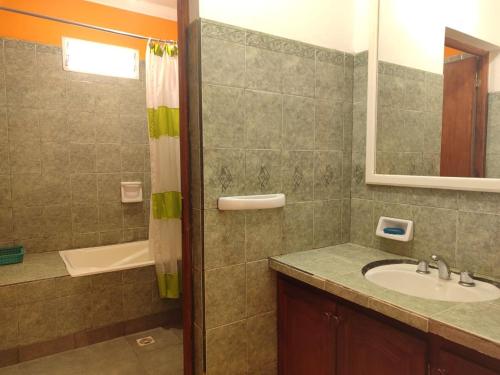 ein Bad mit einem Waschbecken, einer Dusche und einem Spiegel in der Unterkunft VelayWasi in Humahuaca