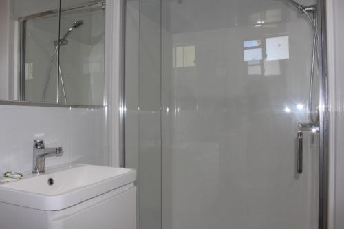 ein weißes Bad mit einer Dusche und einem Waschbecken in der Unterkunft Huntsville Caravan Park in Maryborough