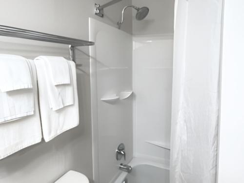 Un baño con toallas blancas y ducha. en Quality Inn Fort Worth - Downtown East, en Fort Worth