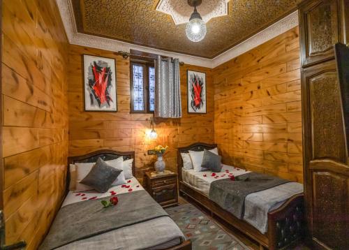twee bedden in een kamer met houten wanden bij Dar Zerbtana Apartment in Fès
