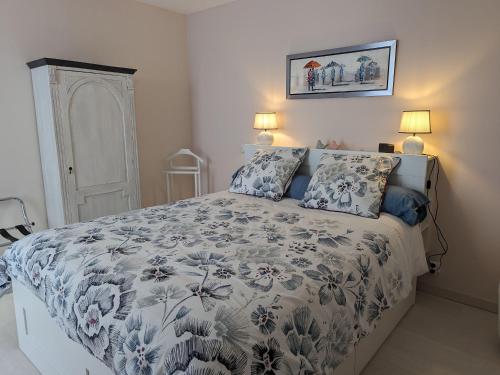 a bedroom with a bed with a blue and white comforter at Gîte Beaugency, 3 pièces, 2 personnes - FR-1-590-196 in Beaugency