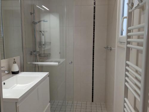 een witte badkamer met een douche en een wastafel bij Gîte Beaugency, 3 pièces, 2 personnes - FR-1-590-196 in Beaugency