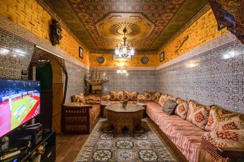 een woonkamer met een bank en een tv bij Dar Zerbtana Apartment in Fès
