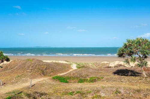 a sandy beach with palm trees and the ocean at Driftwood on the Beach in Yeppoon