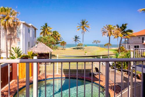 a view of a swimming pool on a balcony with palm trees at Driftwood on the Beach in Yeppoon