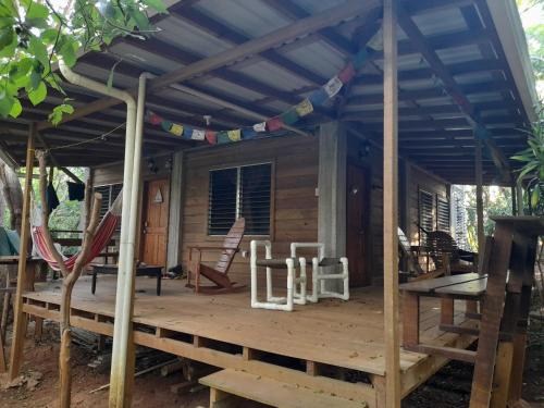 a cabin with a wooden deck with a roof at Apartments Chez Milady in Utila