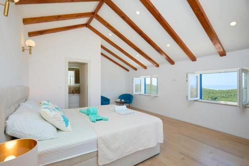 a white bedroom with a bed and windows at Family friendly house with a swimming pool Babino Polje, Mljet - 22326 in Babino Polje