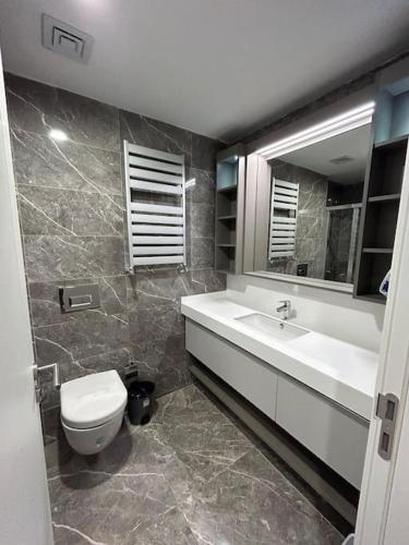 ein Badezimmer mit einem WC, einem Waschbecken und einem Spiegel in der Unterkunft 2+1في اسبارتا كولي in Avcılar