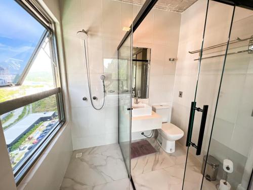 a bathroom with a glass shower and a toilet at PRAIA BRAVA AP Mobiliado Condominio COMPLETO in Itajaí