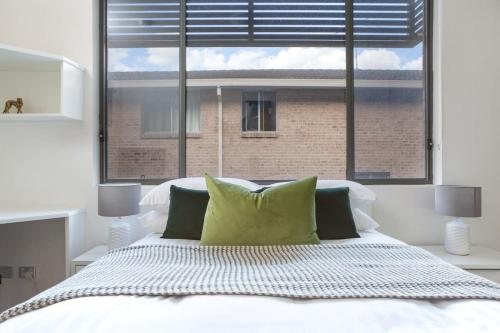 a bedroom with a white bed with a large window at Cosy and Bright Studio Next to Westmead Hospital in Sydney