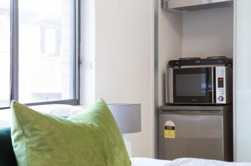 a living room with a microwave on top of a refrigerator at Cosy and Bright Studio Next to Westmead Hospital in Sydney