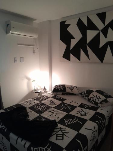 a bedroom with a bed with a black and white comforter at APT PEDRA DO PONTAL Recreio in Rio de Janeiro