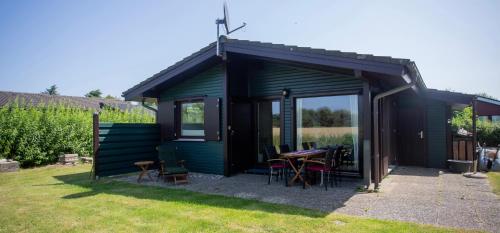 a green shed with a table and chairs in a yard at Lundenbergsand in Simonsberg
