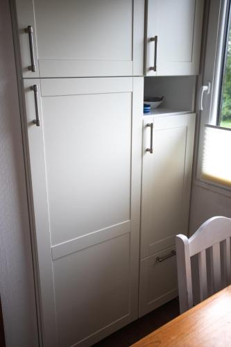 a kitchen with white cabinets and a table and a chair at Lundenbergsand in Simonsberg