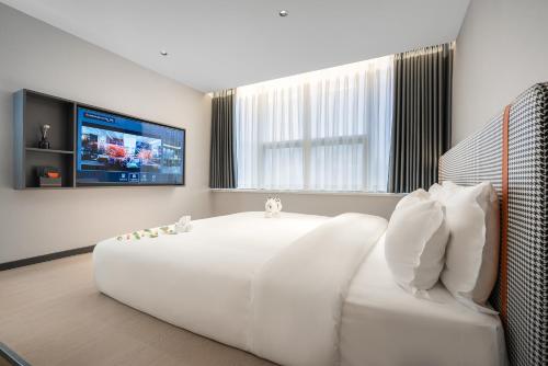 a bedroom with a large white bed and a flat screen tv at R Royalss Hotel, Chengdu Chunxi Road Taikooli Tianfu in Chengdu