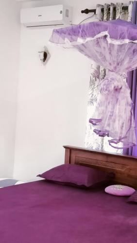 ein Schlafzimmer mit einem Bett mit violetter Bettwäsche und einem Baldachin in der Unterkunft Sunrise Relax Inn in Beruwala
