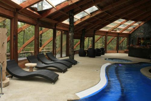 a swimming pool in a pavilion with chairs and a slide at Huilo Huilo Montaña Mágica in Huilo Huilo